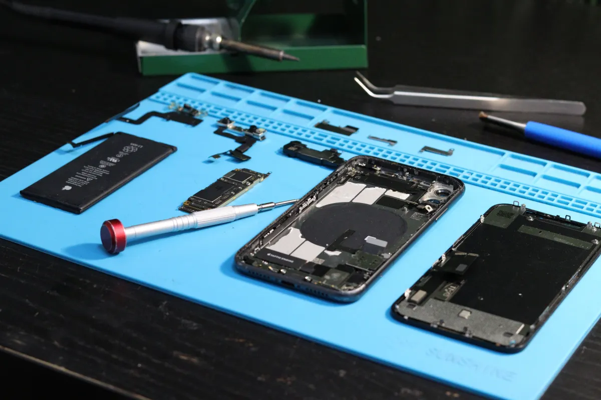 Technicien réparant l'écran d'un smartphone dans un atelier au Maroc